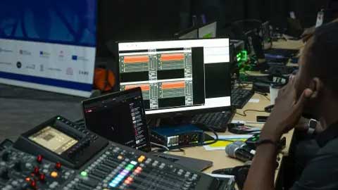 Puzzlepie Zambia Sound Engineering. A sound engineer at his workstation with a computer and a mixing console.